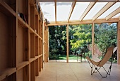 Bat chair with white fabric seat in wooden extension with view of garden