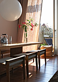 Tisch mit gepolsterten Hockern aus Holz im Designerstil vor offener Balkontür