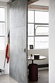 View of round table and stool through open, sliding metal door