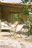 Bank und Liegestuhl auf einer überdachten Terrasse mit Natursteinmauer