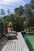 Weathered wooden loungers on deck next to pool in Mediterranean garden