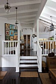 Offener Wohnraum mit Treppe an Empore in ländlichem Wohnhaus mit weisser Holzdecke