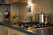 Kitchen counter with gas hob in front of light brown tiled wall