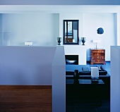 View of black leather couch in front of fireplace through narrow doorway