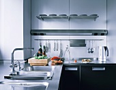 Work surface with stainless steel sink and wall light above hanging kitchen utensils