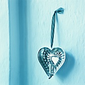 Heart-shaped baking tin used as candle holder hanging on wall