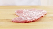 Seasoning veal escalope with salt and pepper