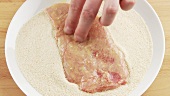 Veal escalope being turned in breadcrumbs