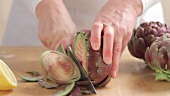 Removing leaf tips from artichokes and sprinkling the cut surface with lemon juice