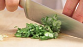 Chopping spring onion leaves into rings