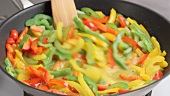 Pepper strips being fried in a pan