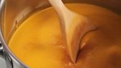 Stirring cream of tomato soup with a wooden spoon