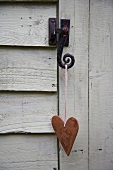 Heart hanging on latch of wooden door