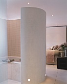 Curved partition around bathtub in open-plan, designer bedroom