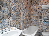 Traditional hotel bathroom with floor-to-ceiling tiling in unconventional mix of patterns