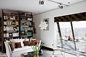 Modernes, junges Wohnzimmer mit Blick durch schräges Panoramafenster auf städtische Kulisse