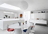 Moderne Designerküche und Essplatz mit Fifties-Retromöbeln im offenen, weissen Wohnraum