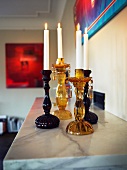 Traditionally-shaped, glass candlesticks on marble mantelpiece