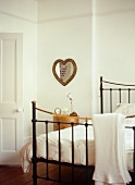 Traditional bedroom with antique-style metal bed and heart-shaped mirror