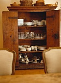 Porcelain and silverware in antique wooden cupboard with open doors