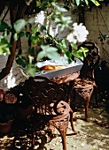 Small seating area on terrace with antique-style metal furniture and simple wooden tray