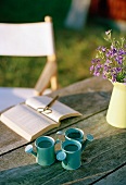 Ornamental miniature watering cans and open book on table