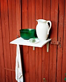 Still-life of washing utensils on shelf mounted on rust-red wall of house