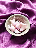 Cloves of garlic in bowl on purple cloth