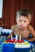 A boy blowing out birthday cake candles