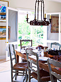 Chandelier hanging above set table in front of open door with view of garden