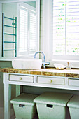 Washing baskets stored beneath rustic washstand with drawers in bathroom