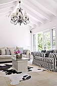 Couch with black and white striped cover and animal-skin rug on floor of simple, renovated country house