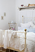 Shabby chic bedroom - vintage metal bed with romantic bed linen and antique washstand in background