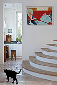 Semi-circular stairs in stone-flagged hallway with view into kitchen
