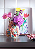 Still-life in kitchen - tulips in ceramic vase with floral decoration and child's drawing of vase of flowers