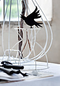Black bird ornament on white-painted metal frame