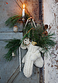 Advent arrangement of mittens, branches, baubles and pine cones on door