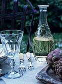 Carafe of white wine and rustic wine glass on set table in garden