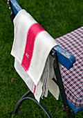 Garden chair with cushion and tea towels hanging over back