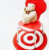 Teddy bear on a red 'Bauhaus' shell chair