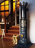 Old cylindrical cast iron stove next to stairs in a living room with an open door