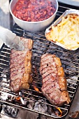 Beef steaks, tomato beans and macaroni and cheese on a grill