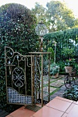 Old, decorative iron gate on wide steps and view into sheltered, Romantic terrace garden