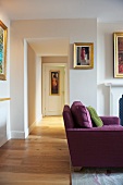 Violettes Sofa im Wohnraum mit offenem Durchgang und Blick in Flur