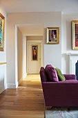 Purple sofa in living room with open doorway and view of hall