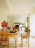 Rustikaler Essplatz mit Kunstobjekt auf Tisch und Blick durch geöffnete Flügeltüren in Küche