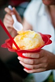 A person eating shaved ice out of an ice cream dish