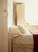 View of bed with white bed linen through open door