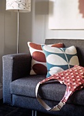 Scatter cushions with abstract floral covers and retro handbag on sofa