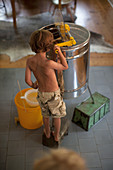 A boy standing by a honey extractor
